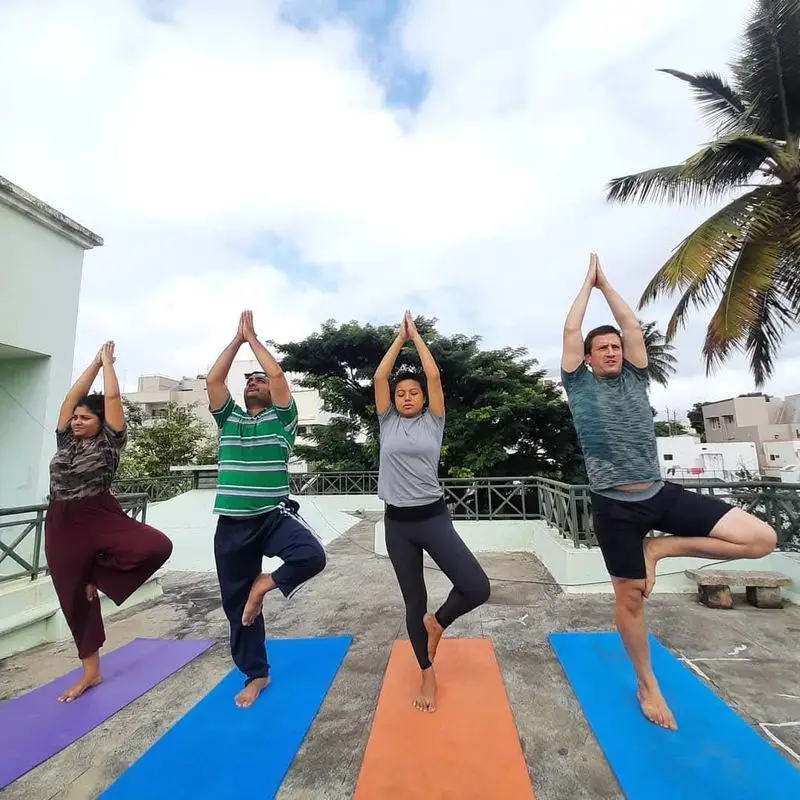Four people sitting cross-legged on mats at a yoga teacher training in Mysore.